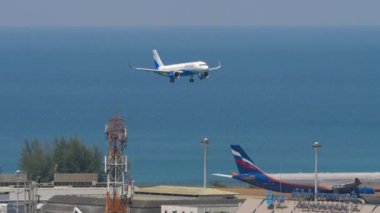 PHUKET, THAILAND - 20 Şubat 2023: Aircraft Airbus A320, Indigo VT-IIP Phuket havaalanına inişe geçiyor. Yolcu uçağı geliyor. Uçak mavi denizin üzerinde uçar.