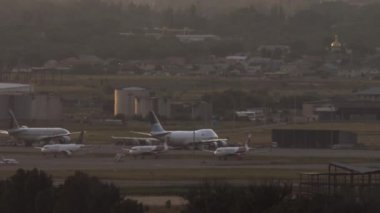 Havaalanı ve uçakların panoramik görüntüsü. Gün batımında otoparkta sıra sıra bekleyen uçaklar.