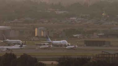 ALMATY, KAZAKHSTAN - 26 Haziran 2024: Terminale park edilmiş kargo ve yolcu uçakları. Havaalanı gün batımının sıcacık ışığıyla aydınlanır..