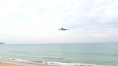 PHUKET, THAILAND - 18 Ocak 2025: Airbus A340, Edelweiss Havaalanı 'nın HB-JMG' si. Yolcu uçağı denizin üzerinden iniyor. Kumsaldaki insanlar, tepemizde uçan bir uçak.