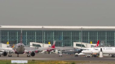 ALMATY, KAZAKHSTAN - 27 Haziran 2024: Airliner Airbus A320, EI-KBN of Fly Arystan Almaty havaalanında taksicilik. Terminalde kürek uçakları, önlük. Yolcu uçağı. Seyahat kavramı