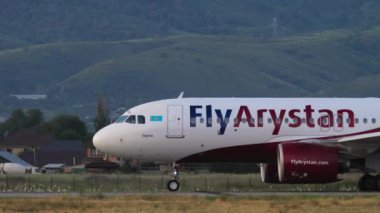 ALMATY, KAZAKHSTAN - 24 Haziran 2024: Airbus A320, EI-KBV FlyArystanon Almaty havaalanı pisti. Arkaplanda dağlar