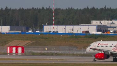 MOSCOW, Rusya Federasyonu - 31 Temmuz 2021: Sukhoi Superjet 100, RA-89114 Rossiya taksisi, yan görüş. Taksideki ya da pistteki yolcu uçağı. Beneklenme