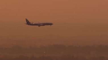 ALMATY, KAZAKHSTAN - 26 Haziran 2024: Boeing 737 SCAT Airlines 'ın gün batımında iniş yaptığı sinema görüntüleri. Uçak uçuşu, yan görüş, uzak çekim.