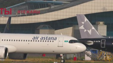ALMATY, KAZAKHSTAN - 27 Haziran 2024: Airliner Airbus A321, Air Astana 'dan EI-KDG Almaty havaalanındaki terminale gidiyor, yan görüş. Seyahat kavramı