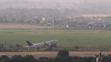 ALMATY, KAZAKHSTAN - 26 Haziran 2024: Almaty Havaalanı 'ndan Astana Hava Yolları uçağı havalandı. Uçak kalkıyor, uzak plan, yan görüş. Uçak kalkıyor. Beneklenme