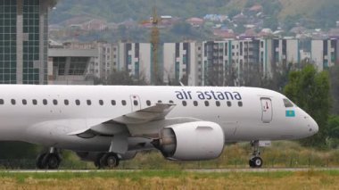 ALMATY, KAZAKHSTAN - 24 Haziran 2024: Hava Astana 'nın Embraer E190' ı Almaty havaalanında taksicilik yapıyor. Arka planda dağlar. Seyahat kavramı