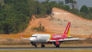 PHUKET, THAILAND - 14 Şubat 2025: Ticari yolcu uçağı Airbus A320-214, Tayland Vietnam Jet Air 'den HS-VKQ Phuket Havaalanı' na indikten sonra fren yapıyor, yan görüş. Spoiler hazır.