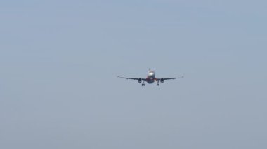Farlarıyla iniş için yaklaşan bir jet uçağının uzaktan görüntüsü. Uçak geliyor.