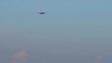 Uçak iniş yapıyor, ön görüş. Tanımlanamayan bir üniformayla gelen bir jet uçağı. Mavi gökyüzünde uçaklar