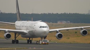 FRANKFURT AM MAIN, ALMANY - 20 Temmuz 2017: Frankfurt Havalimanı 'ndaki StarAlliance üniformasında Lufthansa' nın Airbus A340 'ını çeken traktör
