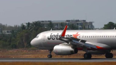 PHUKET, THAILAND - 14 Şubat 2025: Jetstar Asia Airbus A320-232, 9V-JSQ, iniş sonrası yavaşlıyor, yan görüş. Spoiler verilmiş uçaklar geliyor.