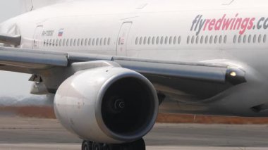 PHUKET, THAILAND - 14 Şubat 2025: Red Wings Boeing 777, RA-73330, taksicilik. İniş takımlarına ve motorlara odaklan.