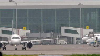 Terminalin arka planında tanımlanamayan bir üniforması olan bir yolcu uçağı.