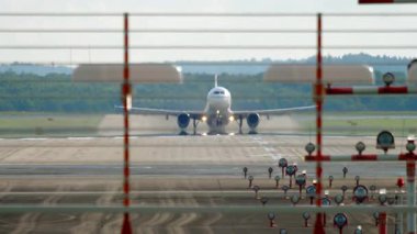 Uçak kalkıyor, pistin sonundan görüntü alıyor. Bir sonraki uçak inişe geçiyor. Gökyüzünde iki uçak, turizm ve seyahat konsepti