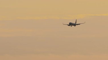 İniş takımlı uçak, altın günbatımı gökyüzüne inmeden önce iniyor. Düşük ihtimal. Uçan bir uçağın görüntüsü. Uçak biletlerinin satışı ve turlar için konsept reklamlar