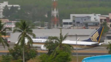 PHUKET, THAILAND - 09 Mart 2025: Boeing 737 MAX 8, 9V-MBA Singapur Havayolları Phuket Havaalanı 'na indikten sonra fren yapıyor. Yolcu uçağı geliyor. Spoiler hazır.