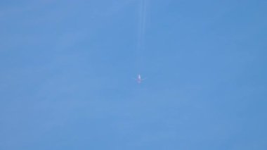Gökyüzünde bir jet uçağı, arkasında hafif bir iz. Mavi gökyüzünde uzun bir jet uçağı sahnesi.