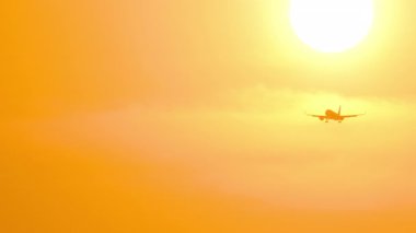 Tanımlanamayan bir üniformayla altın bir günbatımına inen bir jet uçağının sinematik çekimi. Seyahat kavramı