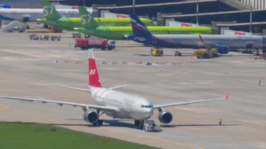 SOCHI, RUSSIA - 27 AĞUSTOS 2022: Airbus A330, RA-73328 Nordwind Havayolları çekici. Traktör ve uçak takside. Meşgul havaalanı