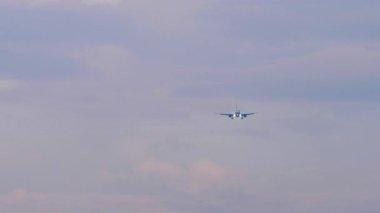 Tanımlanamayan bir üniforması olan jet uçağı inişe geçiyor, ön görüş, uzak çekim.