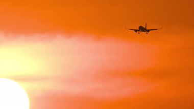 Altın gün batımında gökyüzüne iniş yapmak üzere olan bir uçak görüntüsü. Uçak uçuyor. Seyahat Reklam Arkaplanı