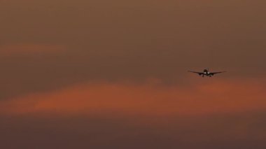 Uzun vadeli karanlık siluet uçağın gün batımının görüntüleri. Uçak inişe geçiyor.