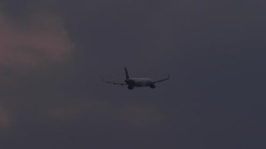 Bulutlu gece gökyüzünde kaybolan bir jet uçağının silueti. Hava yolculuğu, macera ve küresel bağlantı. Turizm, havacılık ve şehirlerarası seyahatler için ideal.