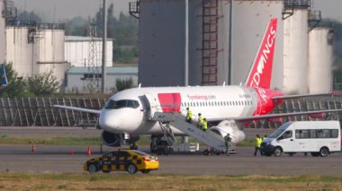 ALMATY, KAZAKHSTAN - 25 Haziran 2024: Sukhoi Superjet 100, RA-89144 Red Wings uçağı havaalanında. Havaalanı personeli uçağa bindi.