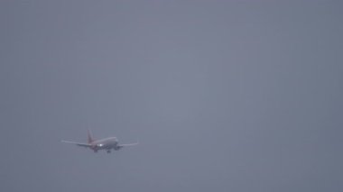 İniş için inen ticari bir uçağın uzaktan görüntüsü. Seyahat, turizm ve küresel havacılık temaları için mükemmel.