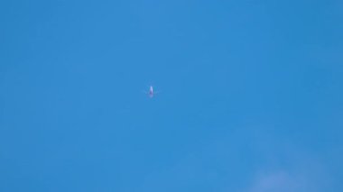 Açık mavi gökyüzünde yüksek uçan bir jet uçağının uzaktan görüntüsü. Minimalist hava sahnesi seyahat, özgürlük ve havacılık temaları için mükemmel.