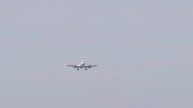 Bulutlu gökyüzünde bir uçak. İnişe geçen uçak, uzak plan, ön görüş. Yolcu uçağı geliyor. Seyahat kavramı