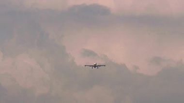Bir uçağın güzel bulutlu bir günbatımı gökyüzüne inişi görüntüsü.