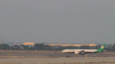 BANGKOK, THAILAND - 16 Mart 2025: Suvarnabhumi havaalanında taksicilik yapan geniş gövdeli EVA Air Boeing 777. Uçak havaalanında, yan görüş. Seyahat kavramı