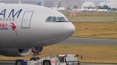 FRANKFURT AM MAIN, ALMANY - 20 Temmuz 2017: Airbus A330, B-6538 Çin Doğu Havayolları çekici. Traktör uçak çekiyor. Seyahat kavramı