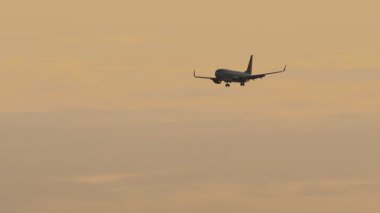 Gün batımına karşı jet yolcu uçağı. Akşam karanlığında uçak silueti. Uçuşun, inişin görüntüleri.