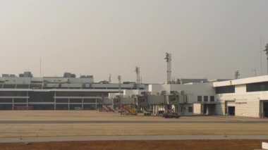 Uçak penceresinden POV görüntüsü havaalanı önlüğünü, boş jet köprülerini ve terminal binasını gösteriyor. Hava aracı olmadan zemin kontrol bölgesi. Seyahat ve havacılık kavramı.