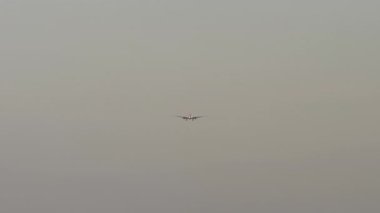 Bulutlu gri gökyüzüne iniş yapan bir jet uçağı yaklaşıyor. Seyahat kavramı