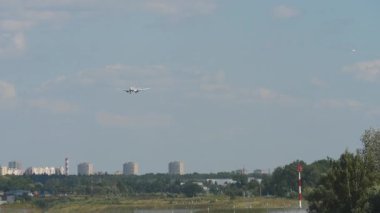 Jet yolcu uçağı uçuyor. Uçak inişe yaklaşıyor, ön görüş, uzak çekim.