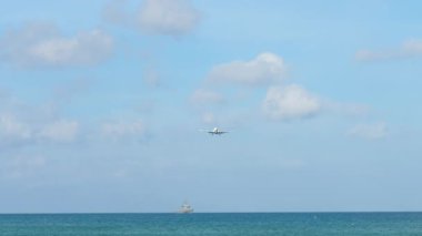 İniş için işaretsiz bir üniforması olan bir jet uçağı, ön görüş için yaklaşıyor. Açık mavi gökyüzüne inen uçak.