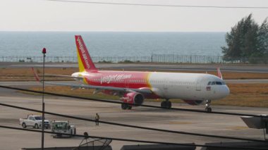 PHUKET, THAILAND - 07 Mart 2025: Phuket Havaalanı 'ndaki Vietnam Jet Air Airbus A321 yolcu uçağı. Seyahat konsepti. Havaalanı ve deniz arka planı