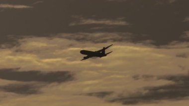 Yolcu jeti bulutlarla dolu dramatik bir günbatımı gökyüzünde süzülüyor. Seyahat, havacılık ve keşif konuları için ideal.