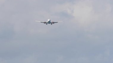 İniş için yaklaşan bir uçak, bulutlu bir gökyüzünün arka planına karşı ön manzara. Havacılık ve seyahat kavramı.