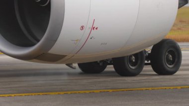 Jet motorunun yakın çekimi ve ticari bir uçağın iniş takımları. Seyahat, yer operasyonları ve modern havacılık teknolojisi.