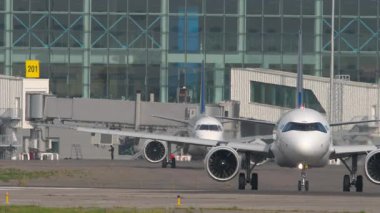 ALMATY, KAZAKHSTAN - 27 Haziran 2024: Air Astana Airbus A321 Almaty Uluslararası Havaalanı, Kazakistan 'da Embraer E190 yakınlarında taksicilik yapıyor. Aktif havaalanı trafik alanı