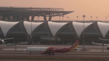 BANGKOK, THAILAND - 15 Mart 2025: VietJetAir Airbus A321, HS-VKJ Suvarnabhumi havaalanında taksicilik. Terminaldeki uçakların sinematik görüntüleri. Seyahat kavramı