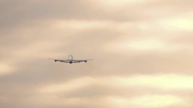 Dört motorlu geniş gövdeli bir jet uçağının çarpıcı bir günbatımında ya da gün doğumunda gökyüzüne tırmandığı görülmektedir. Seyahat ve uzun mesafeli havacılık kavramları.