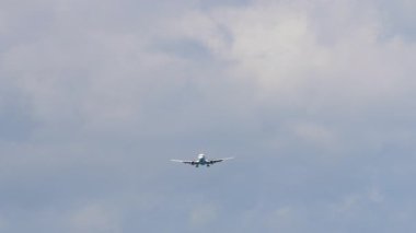 İşaretsiz üniforması olan bir yolcu uçağı bulutlu bir gökyüzünden yaklaşıyor. Uçak inmeye hazırlanıyor. Havacılık ve seyahat temaları için ideal.