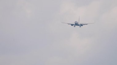 Tanımlanamayan bir üniforması olan bir jet yolcu uçağı iniş yapmak üzere. Gri gökyüzünde uçan uçak. Seyahat konsepti, güvenli uçuşlar, havacılık