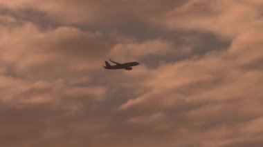 Havalandıktan sonra gökyüzüne uçan kimliği belirsiz bir üniformalı yolcu uçağının çarpıcı bir günbatımı arkaplanına çarptığı bir video.